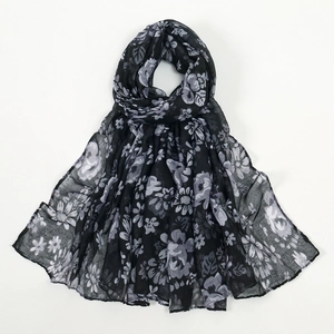 Détail de l'imprimé floral sur une longue écharpe en mousseline noire et fleurs blanches