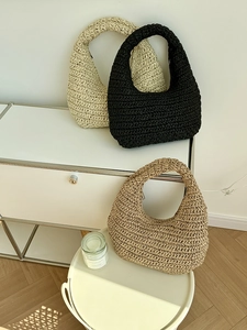 Detailed close-up of handmade woven hobo bags in cream, black and khaki textured knit