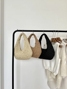 Handwoven hobo shoulder bags in beige, khaki, and black colors displayed on a minimalist rack