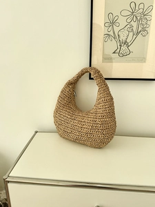 Macro detail of hand-woven straw hobo bag showing natural texture and handle