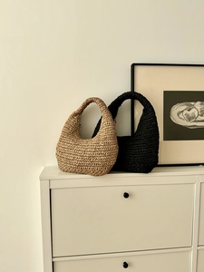Detailed view of woven straw handbags in natural beige and black on a white cabinet
