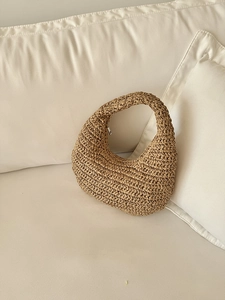 Close-up of handmade khaki woven hobo bag with detailed straw texture on sofa