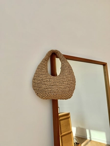 Detail of hand-woven straw hobo bag showing crochet texture and khaki crescent shape