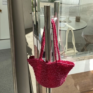 Close-up of handmade fuchsia straw woven bag with intricate chevron texture and handle
