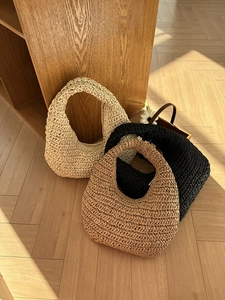 Detailed view of hand-woven cloud shoulder bags in cream, black, and brown straw texture