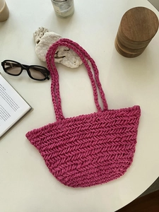 Detail view of rose pink handmade woven shoulder tote bag with decorative beach accessories