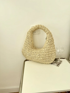 Detailed close-up of cream handmade crochet texture on a half-moon hobo straw bag