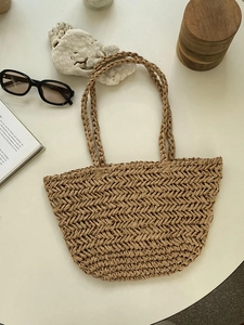 Detail of herringbone weave texture and brown straps on straw tote beach bag