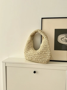 Detail of hand-woven beige straw shoulder bag with unique honeycomb texture