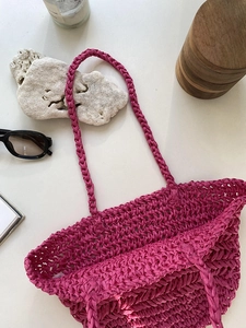 Detail view of pink straw woven bag texture with internal label on white surface