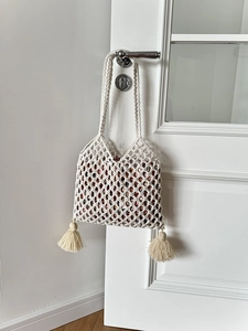 Détail du sac en macramé blanc avec glands décoratifs et pochette à doublure florale