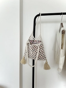 Détail du sac de plage crochet crème avec doublure florale et pompons décoratifs