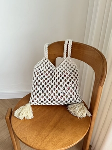 Détail de sac cabas blanc en maille tressée avec pompons latéraux et doublure fleurie