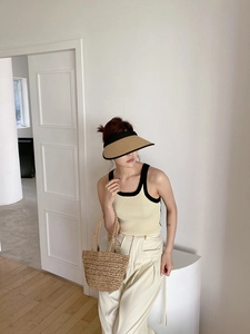 Detail of straw sun visor with black piping and matching woven beach bag for summer
