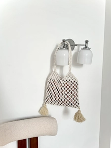 Détail d'un sac en maille tressée avec doublure florale, pompons et texture tissée