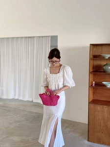 Detail of pink woven handbag paired with white linen puff sleeve top and side slit skirt