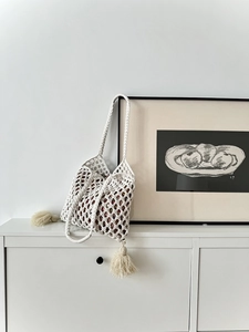 Détail d'un sac en paille blanc fait main avec motif losange évidé et pompons