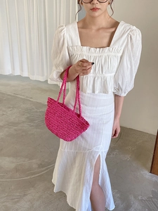 Detail of pink straw woven handbag paired with white elegant puff sleeve top and skirt