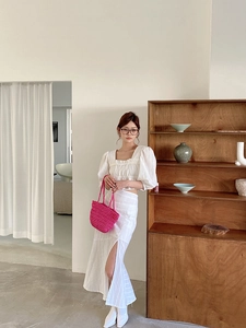 Detail of white puff sleeve crop top and high waist slit skirt for summer beach vacation