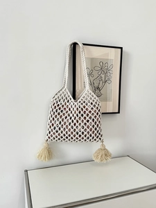 Détail d'un sac à bandoulière en paille avec pompons tissés et doublure florale