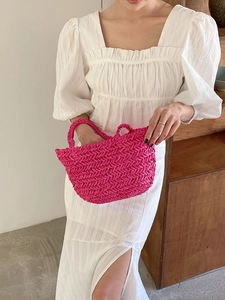 Close-up of rose red straw bag with herringbone weave and matching woven handles