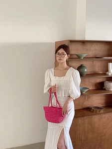 Detail view of pink straw handbag paired with a white two-piece summer beach outfit