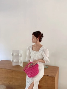 Detail of a bright fuchsia woven tote bag paired with an elegant white summer outfit