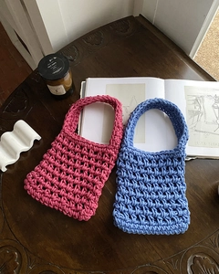Detailed close-up of handmade chunky knit handbags in vibrant pink and blue colors