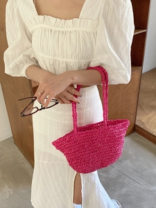 Detail of pink hand-woven straw bag with V-shaped texture and dual handles