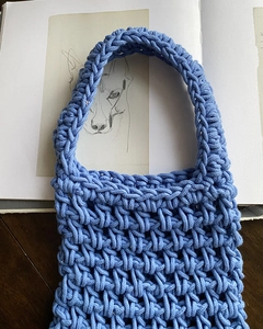 Detail of light blue hand-woven cotton knit handbag with a unique hollow texture