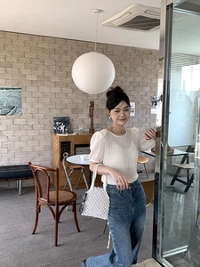 Détail d'un haut en tricot blanc à manches bouffantes avec tissu texturé et col rond