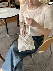 Vue détaillée du sac à main beige tissé à la main avec des textures évidées complexes