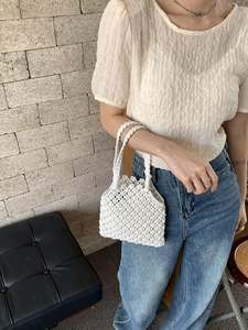 Détail du sac à main crochet blanc montrant la texture ajourée et les anses tressées