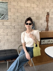 Photo de style d'une femme avec un sac à main tissé vert et un haut blanc texturé chic