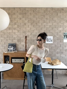 Détail du sac à main en tricot évidé jaune avec haut texturé et jean en denim