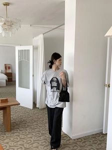 Détail d'un sac à main noir tissé ajouré assorti d'un t-shirt gris et d'un pantalon rayé
