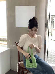 Détail d'un sac à main en paille tressée verte avec textures en corde de coton fait main