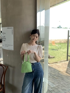 Détail d'un sac cabas vert au crochet porté avec un jean et un haut beige clair élégant