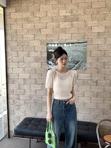 Détail d'un sac à main tissé vert assorti à un haut blanc et un jean bleu rétro