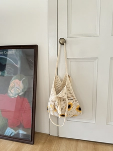 Detailed close-up of ivory crochet flower bag with yellow sunflowers and fringe tassels