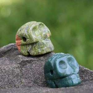 Sculptures de crânes en aventurine naturelle et granit posées sur une roche grise