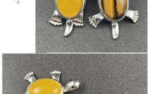 Detail view of turtle pendants featuring yellow gemstones and natural tiger eye stones