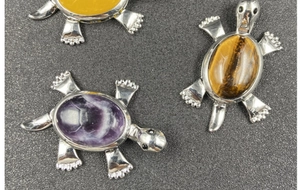Detailed close-up of turtle-shaped brooches set with amethyst and tiger eye stones
