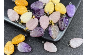 Macro detail of hand-carved natural gemstone leaf pendants with intricate vein patterns