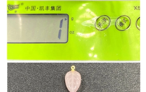 Macro detail of leaf-shaped pink quartz pendant on a digital scale weighing one gram