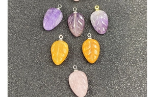 Macro view of leaf-shaped amethyst and rose quartz pendants with detailed vein carvings