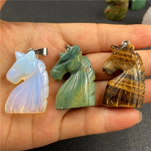 Detail of hand-carved tiger eye, aventurine, and opalite horse head crystal pendants