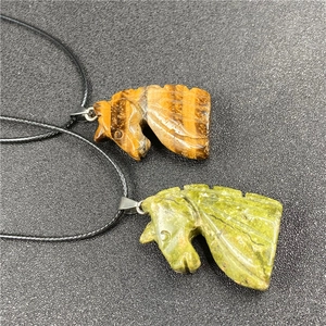 Detailed view of tiger eye stone and green jade unicorn pendants with black cords
