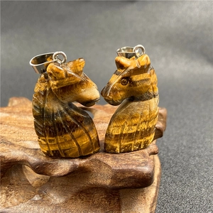 Macro shot of tiger eye stone chess knight pendants with polished silver metal bails