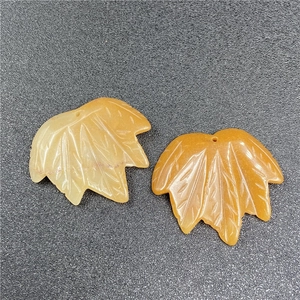 Macro shot of maple leaf stone pendants showing detailed carved veins and textures